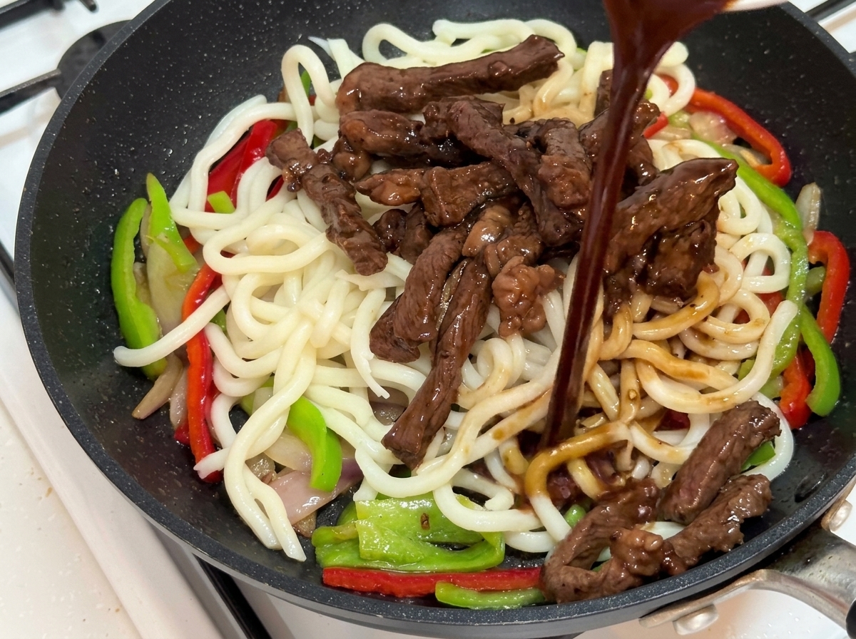 炒め物の上に合わせ調味料を回しかけている様子