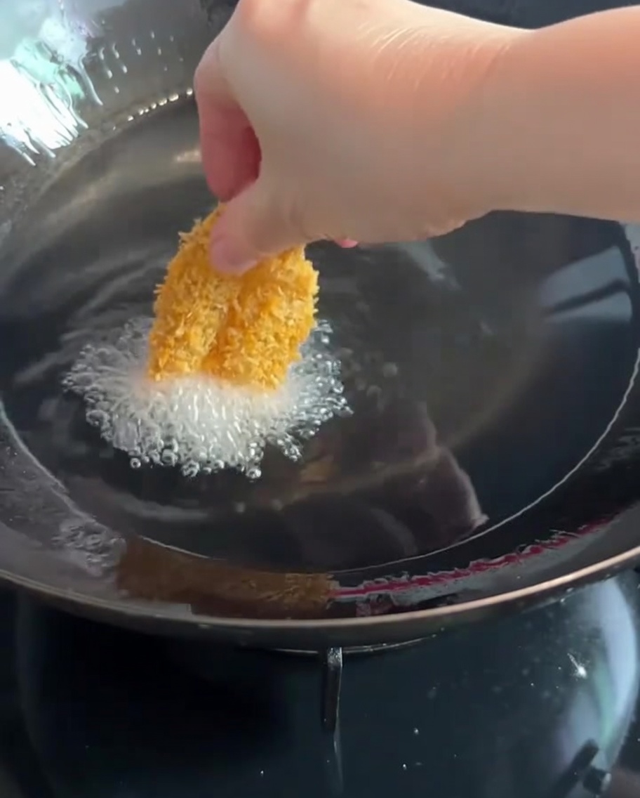 パン粉をつけた海老を熱した油の中に入れている様子。