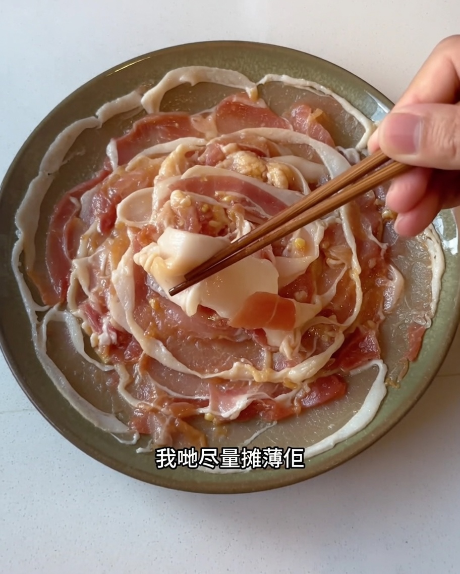 下味をつけた豚バラ肉を、箸を使ってお皿の上に重ならないように広げている様子。