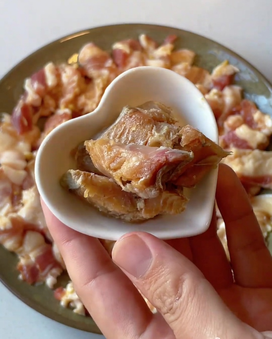 下味をつけた生の豚肉の上に、小さく切った塩漬け魚をのせているクローズアップ画像。