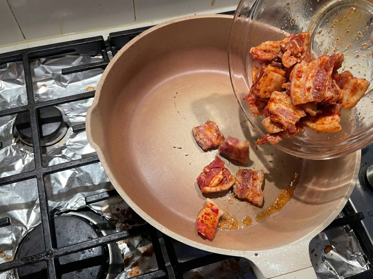 熱したフライパンに marinated 豚肉を入れる様子
