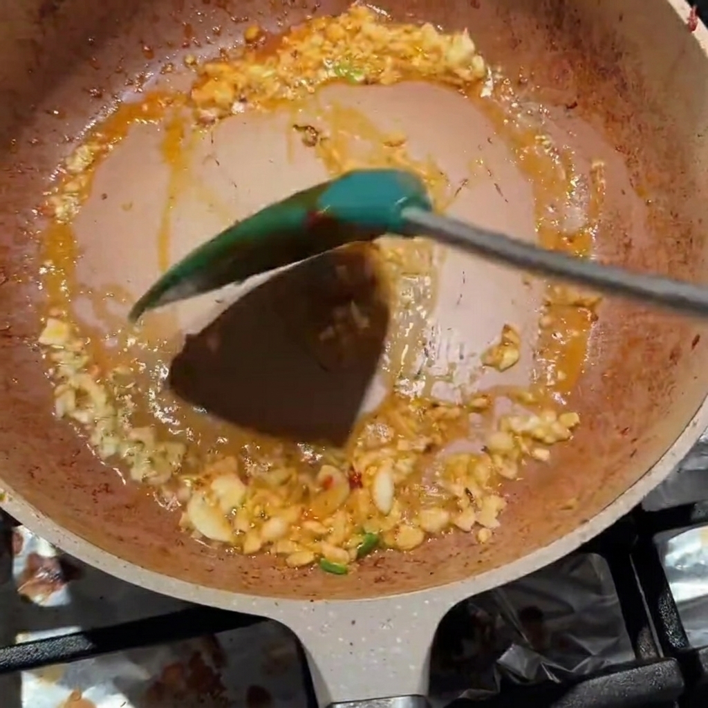 ニンニクと豆板醤を一緒に炒めて調味料をなじませている様子