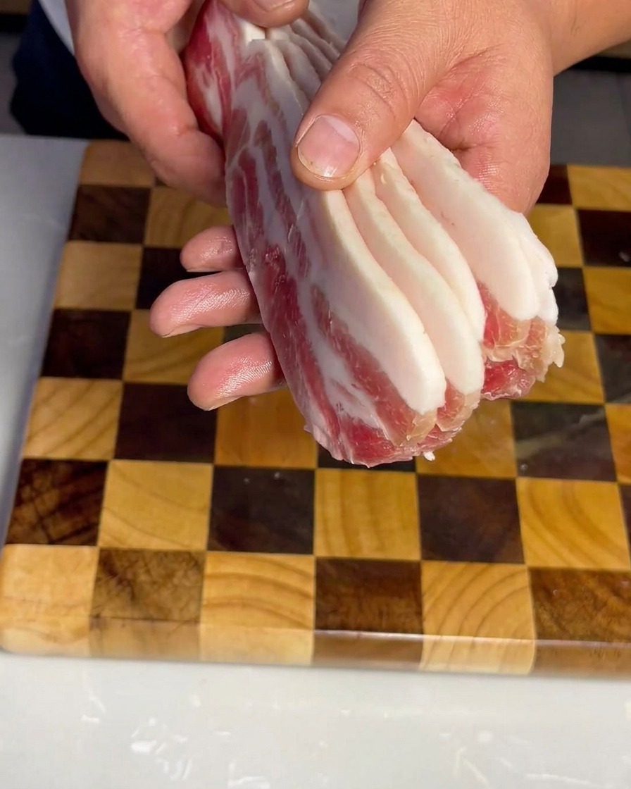 まな板の上に並べられた、均一にカットされた生の豚バラ肉。
