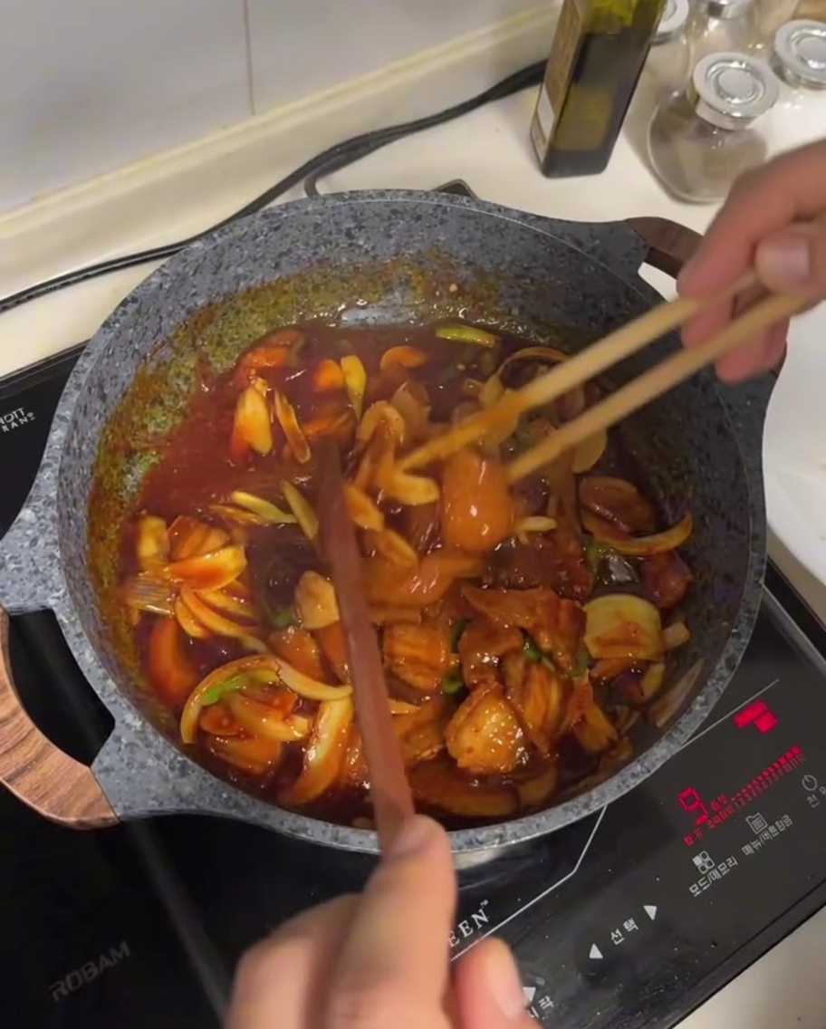 フライパンで肉と野菜をソースで炒めている様子。