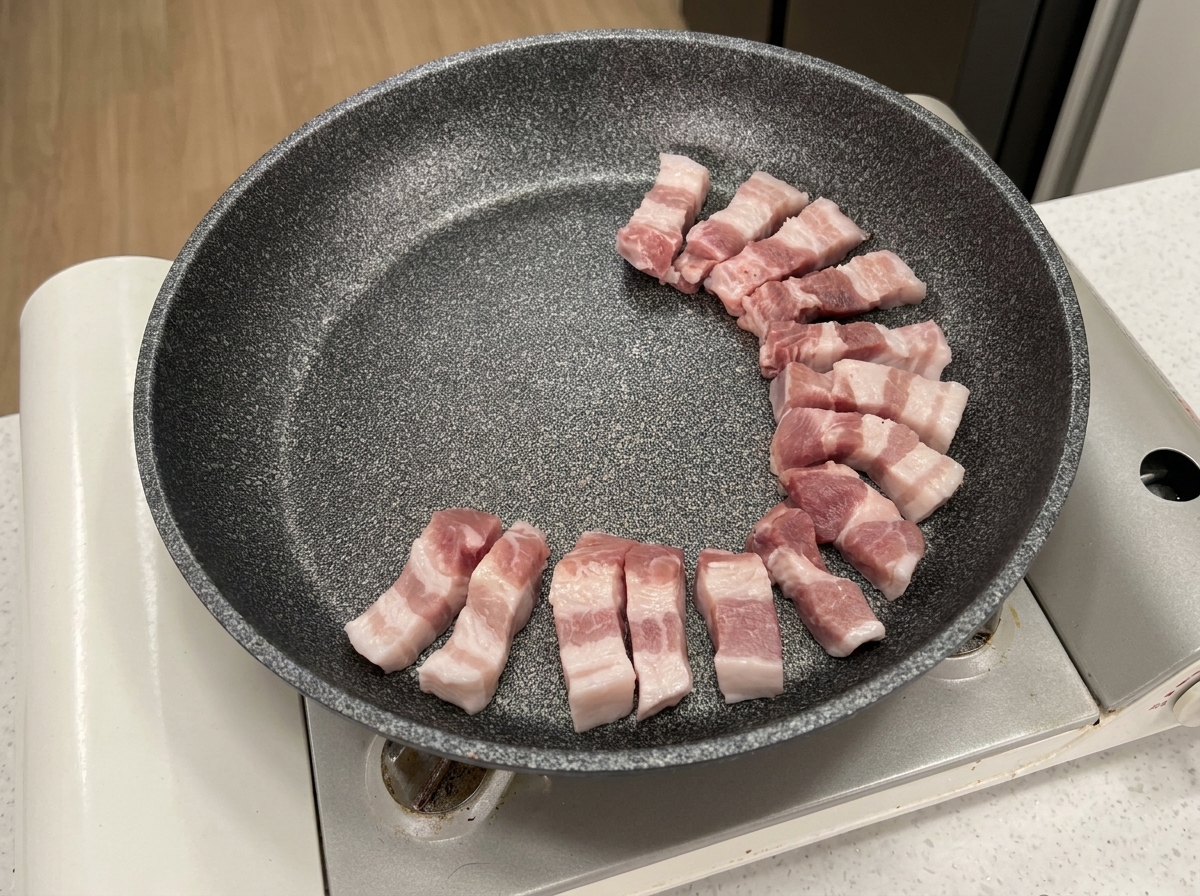 冷たいフライパンに、豚バラ肉を円を描くように並べている様子。