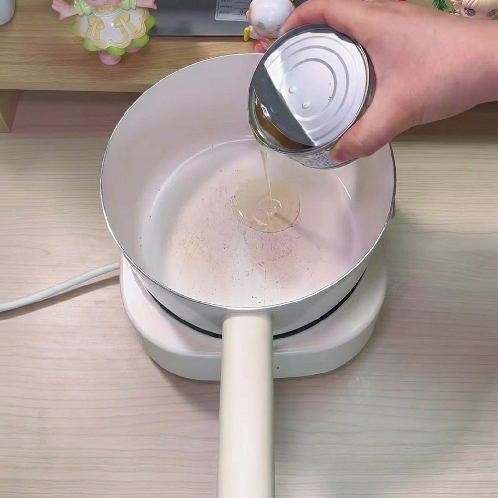 鍋にツナ缶の油を注ぎ入れている様子。