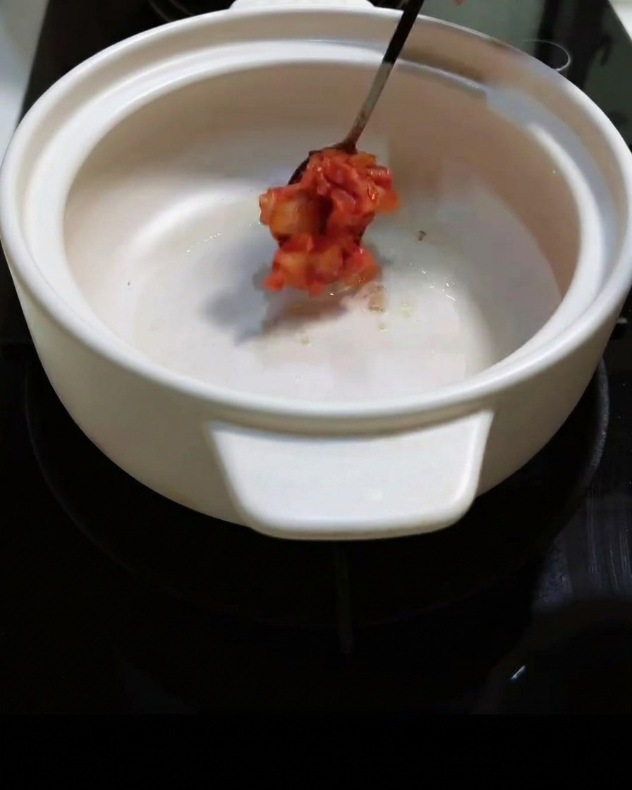 刻んだピリ辛キムチを鍋に入れ、炒めている様子。