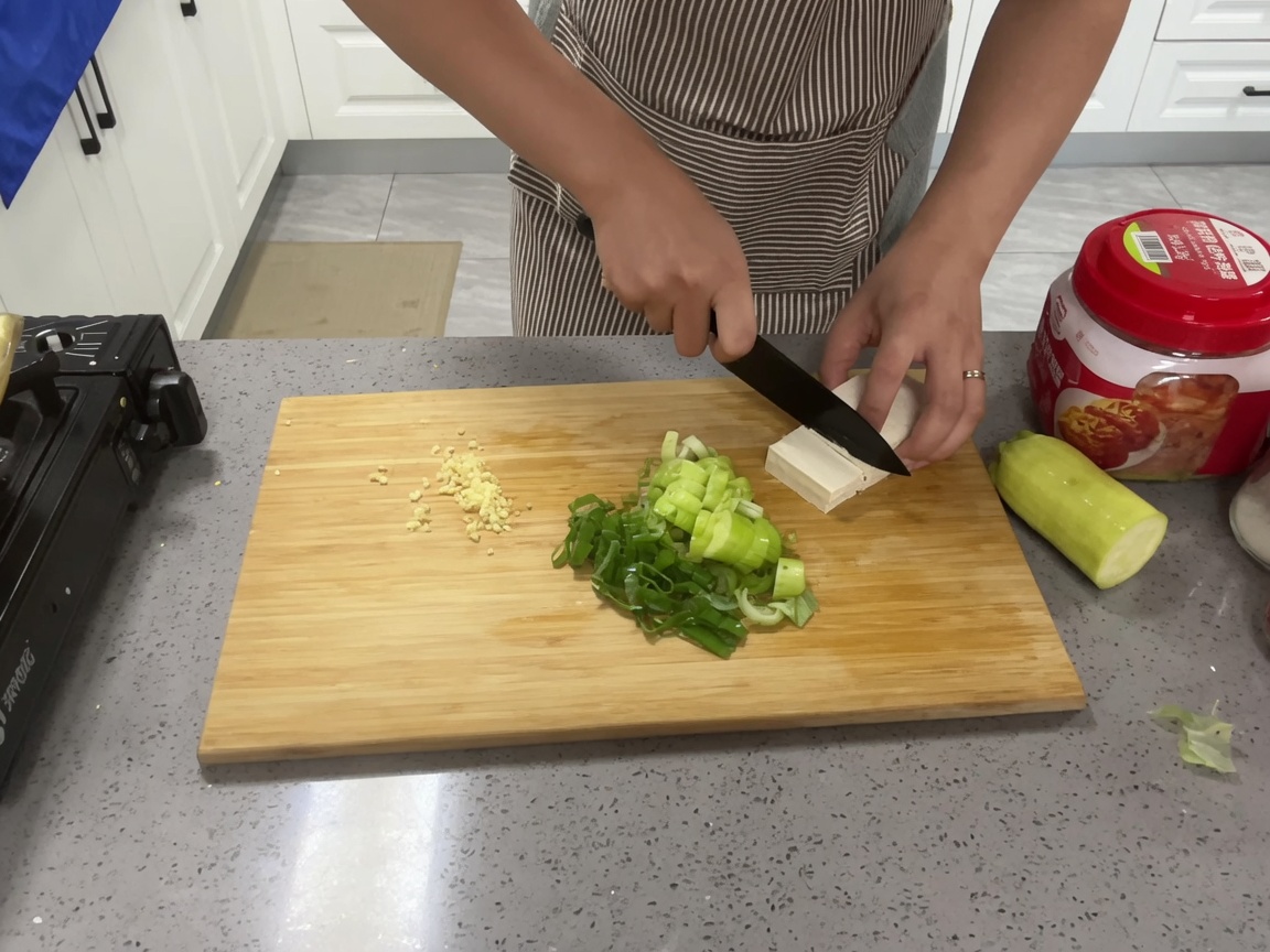 まな板の上で豆腐を一口大の角切りにしている様子。