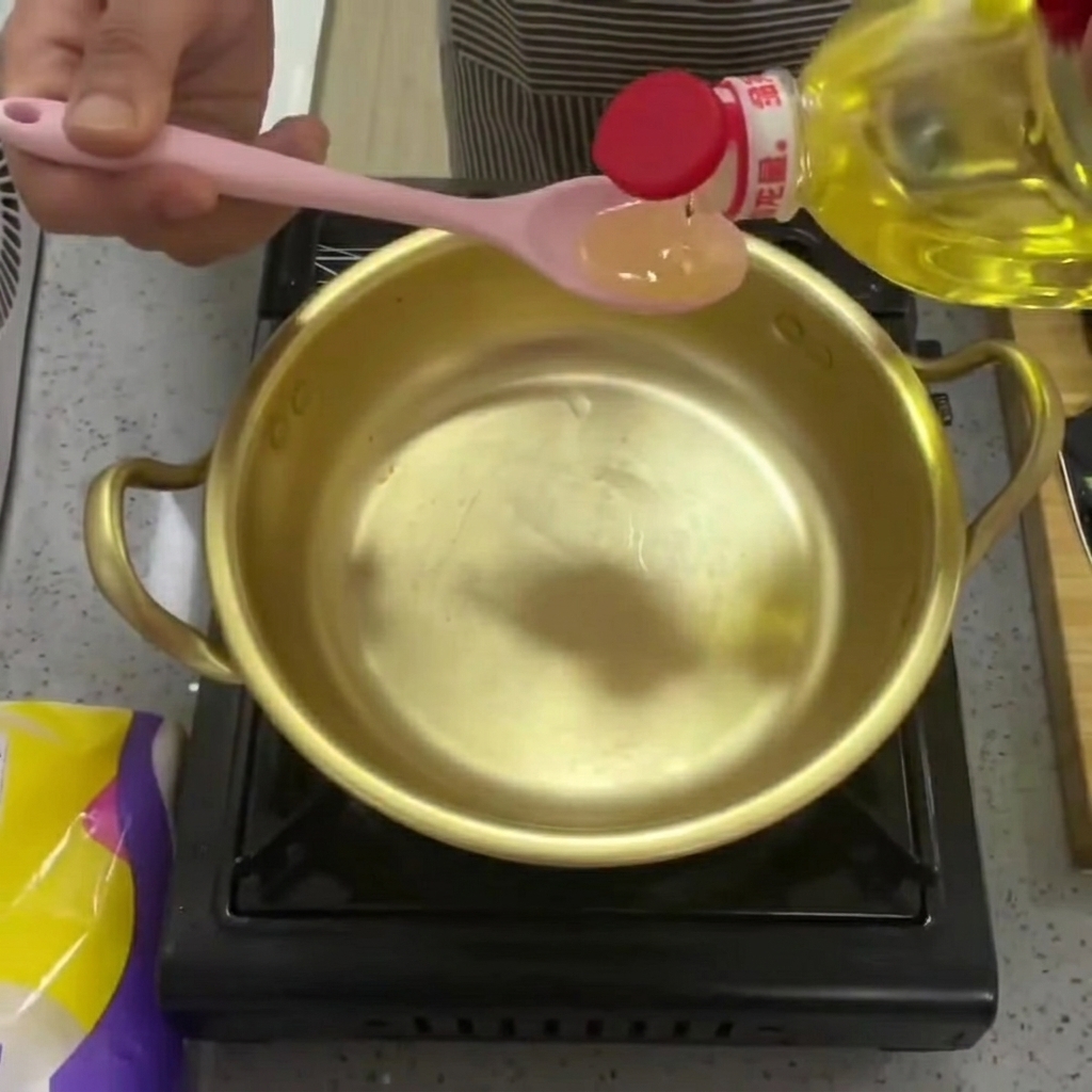 真鍮鍋に透明な調理油を注いでいる様子。