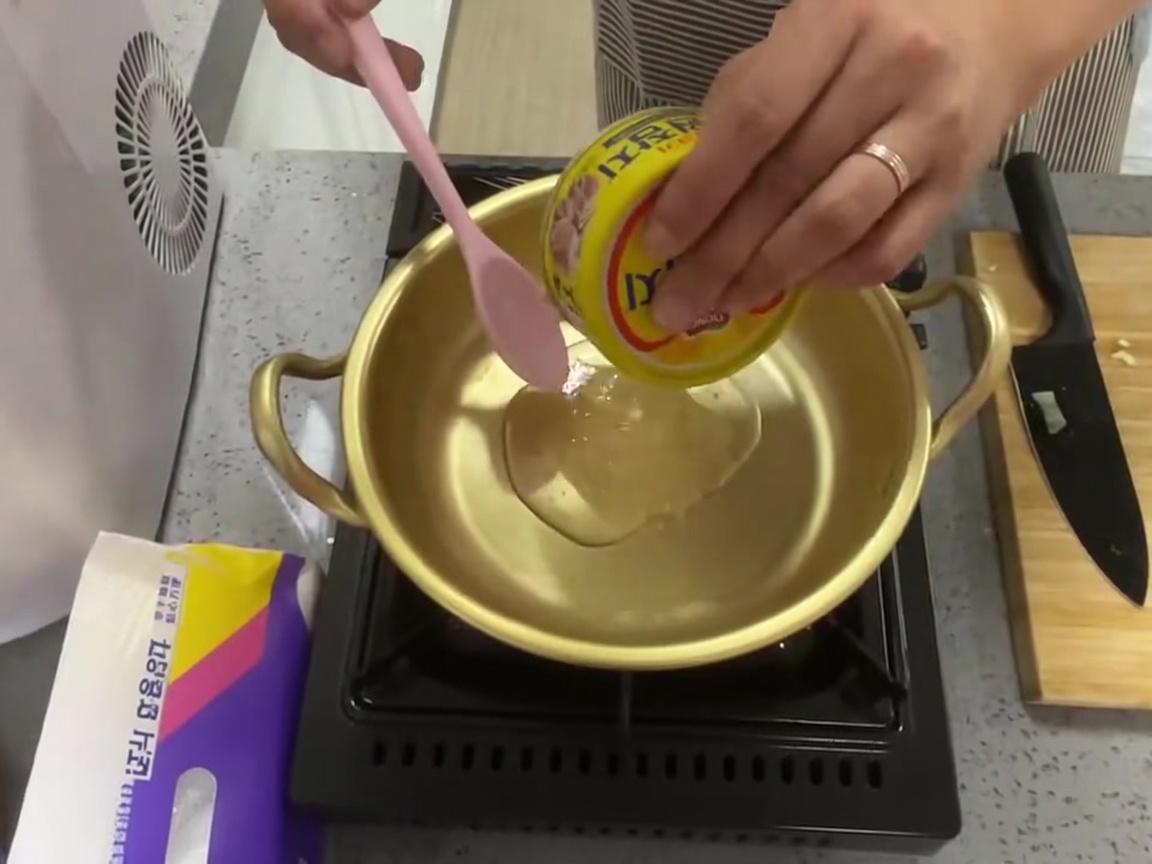ツナ缶から油を鍋に注いでいる様子。