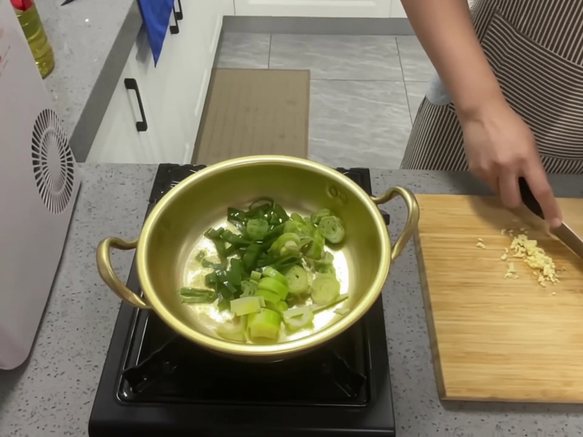 鍋でネギとにんにくを炒めている様子。