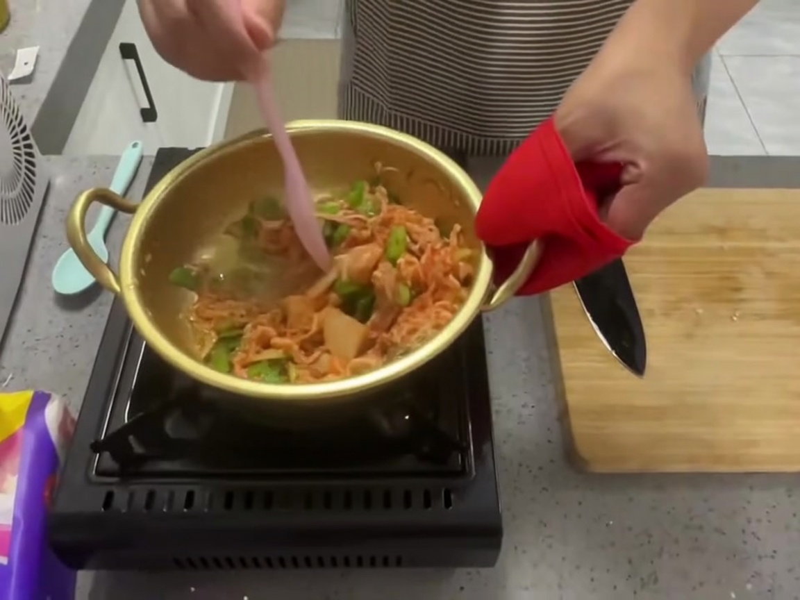 ピンクのスパチュラで鍋の中の具材を混ぜ合わせている様子。