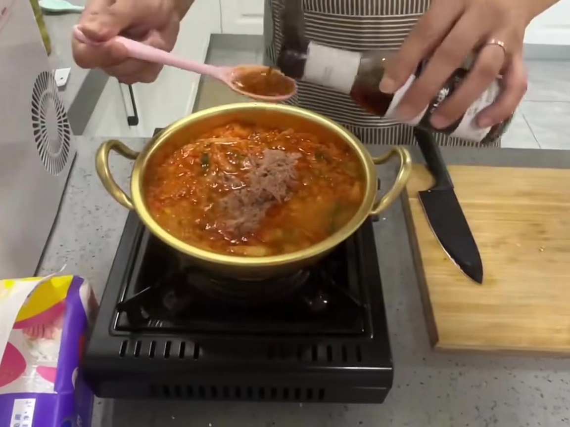 煮立っている鍋に調味料を加えている様子。
