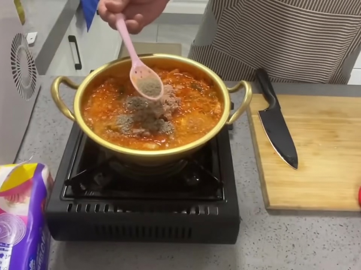 粉末を鍋に振り入れている様子。