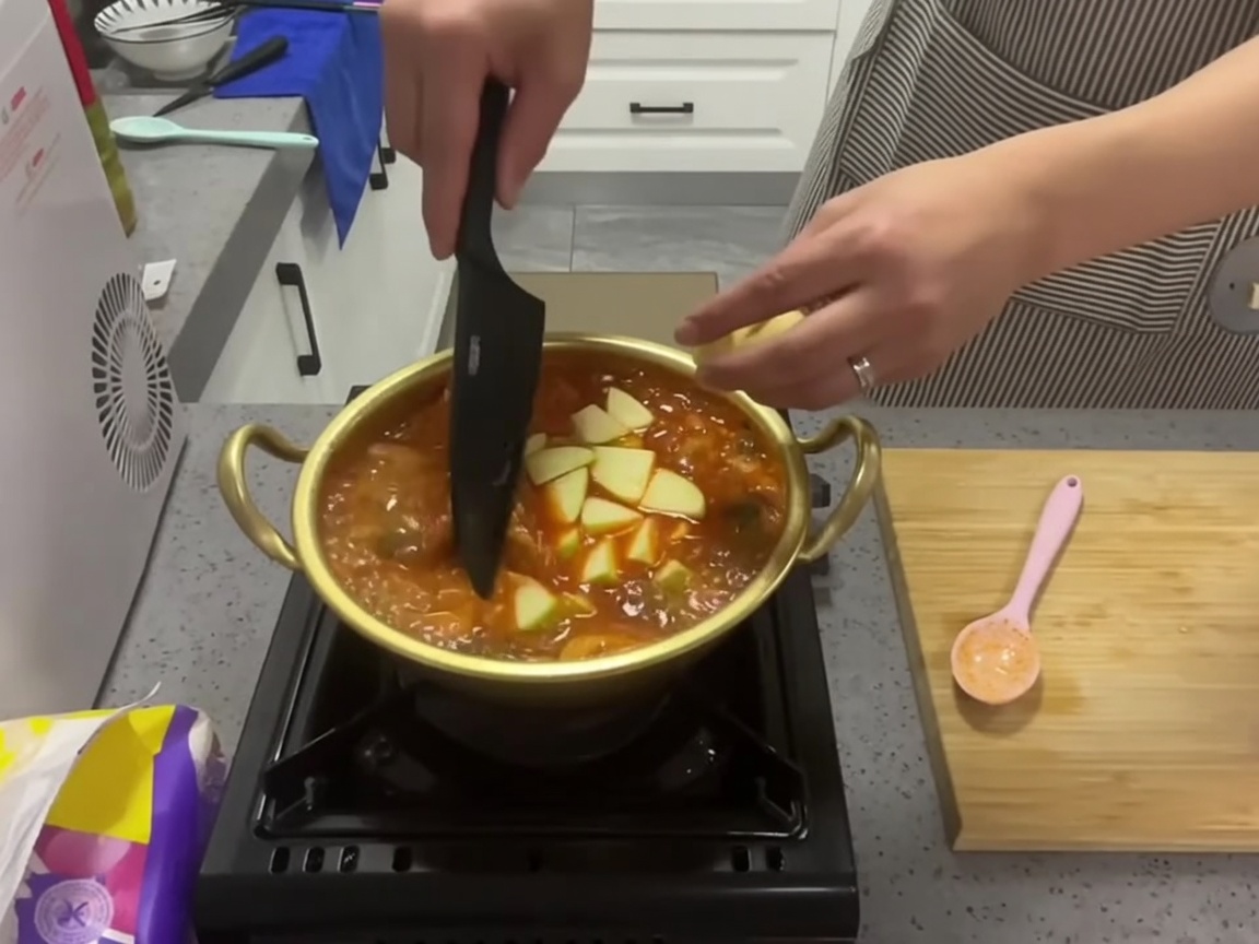 沸騰するスープの中に輪切りのズッキーニを入れている様子。