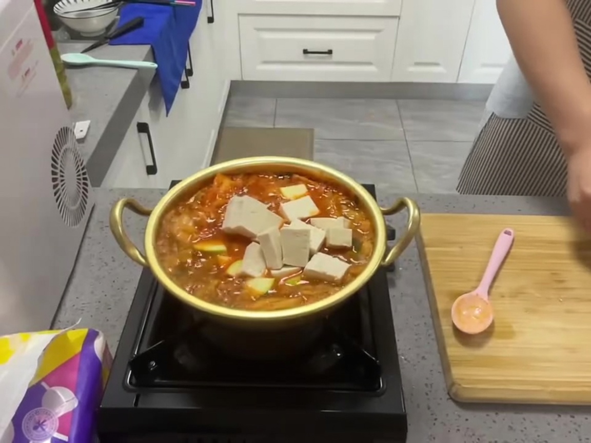 スープに豆腐の角切りを入れている様子。