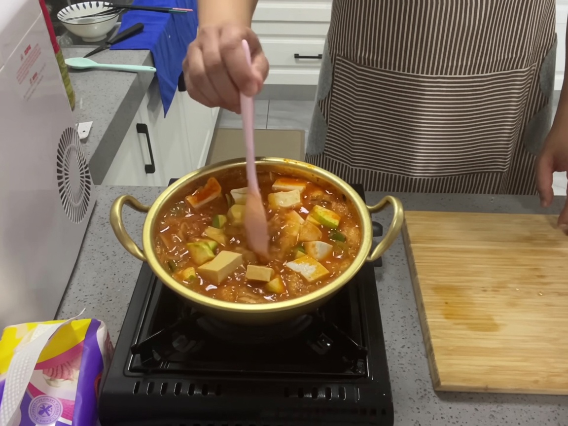 鍋の中の具材を軽く混ぜ合わせ、ぐつぐつと煮込んでいる様子。