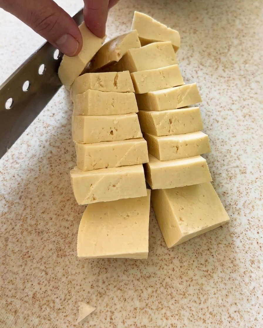 まな板の上で豆腐を均一な形に切り分けている様子。