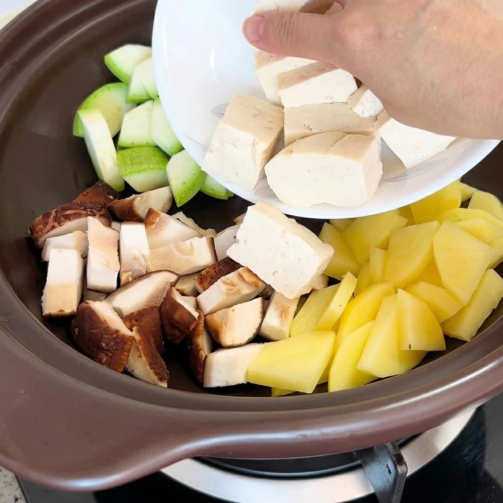 他の野菜が入った鍋に豆腐と干し貝を慎重に加えている様子。