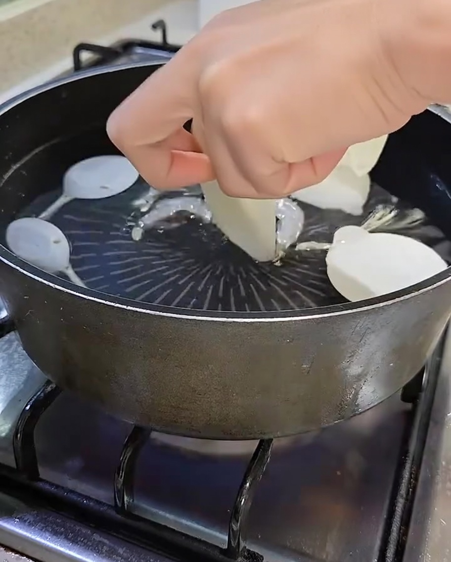 煮干し、椎茸、薄切りの大根、ねぎが沸騰した湯に入っている鍋。