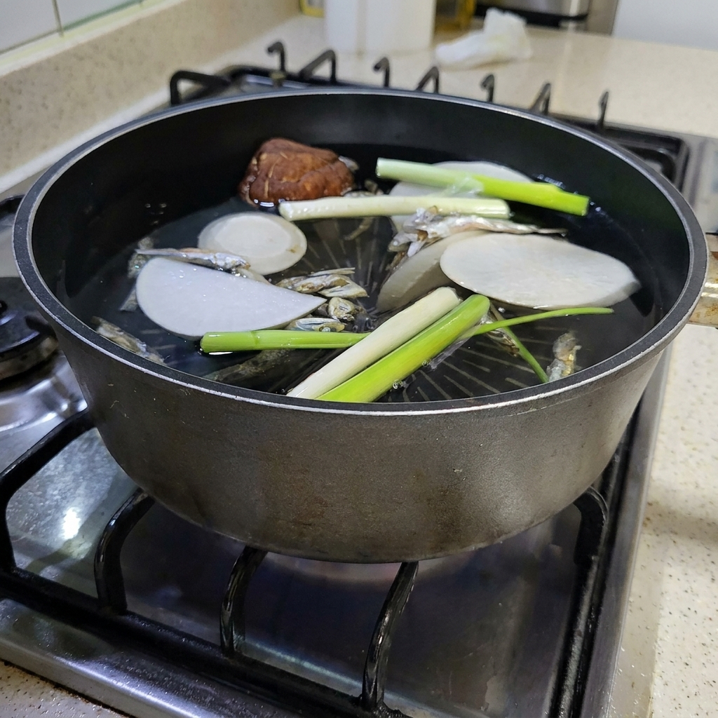 沸騰しただし汁の鍋に大きな昆布が加えられている様子。