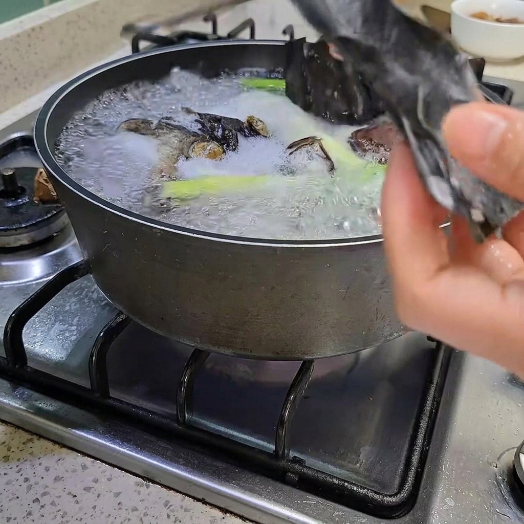 沸騰した鍋からトングで昆布を取り出している様子。