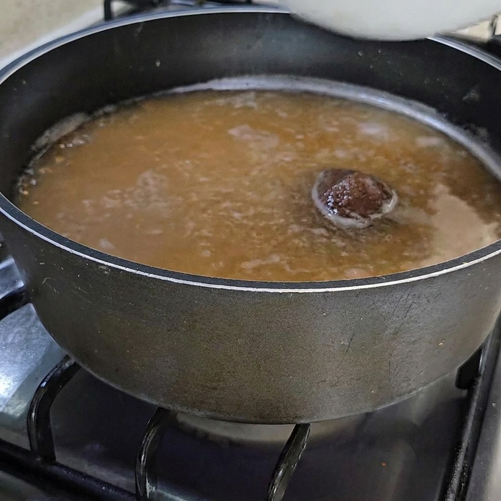 ぐつぐつ煮える味噌スープに、新鮮なオレンジ色のホヤを加えている様子。