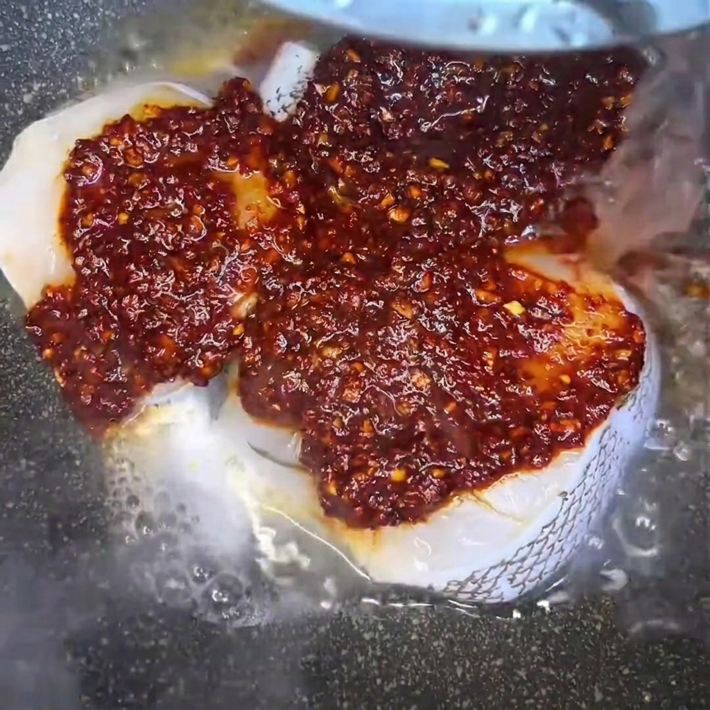 タラの入った鍋に水を注ぎ入れ、煮汁を作っている様子。