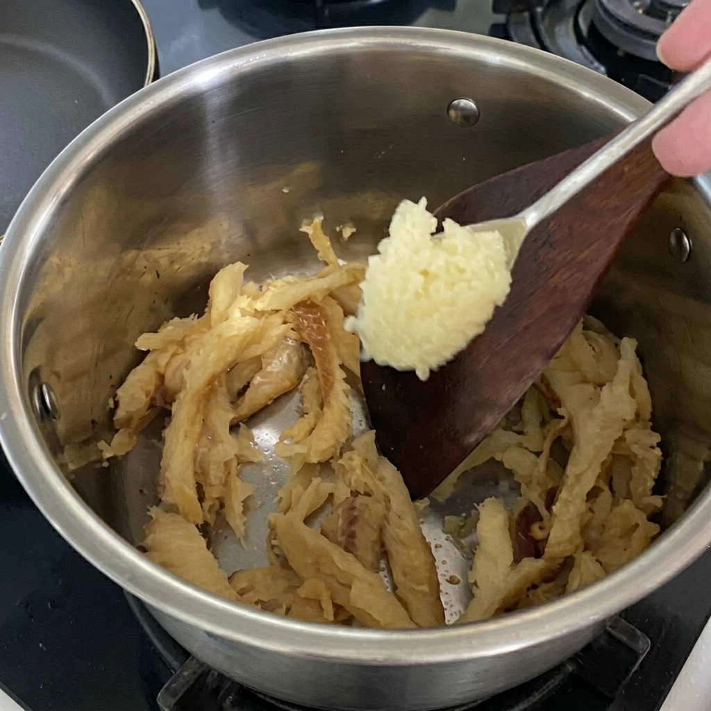 炒めているタラにおろしにんにくを加える様子。
