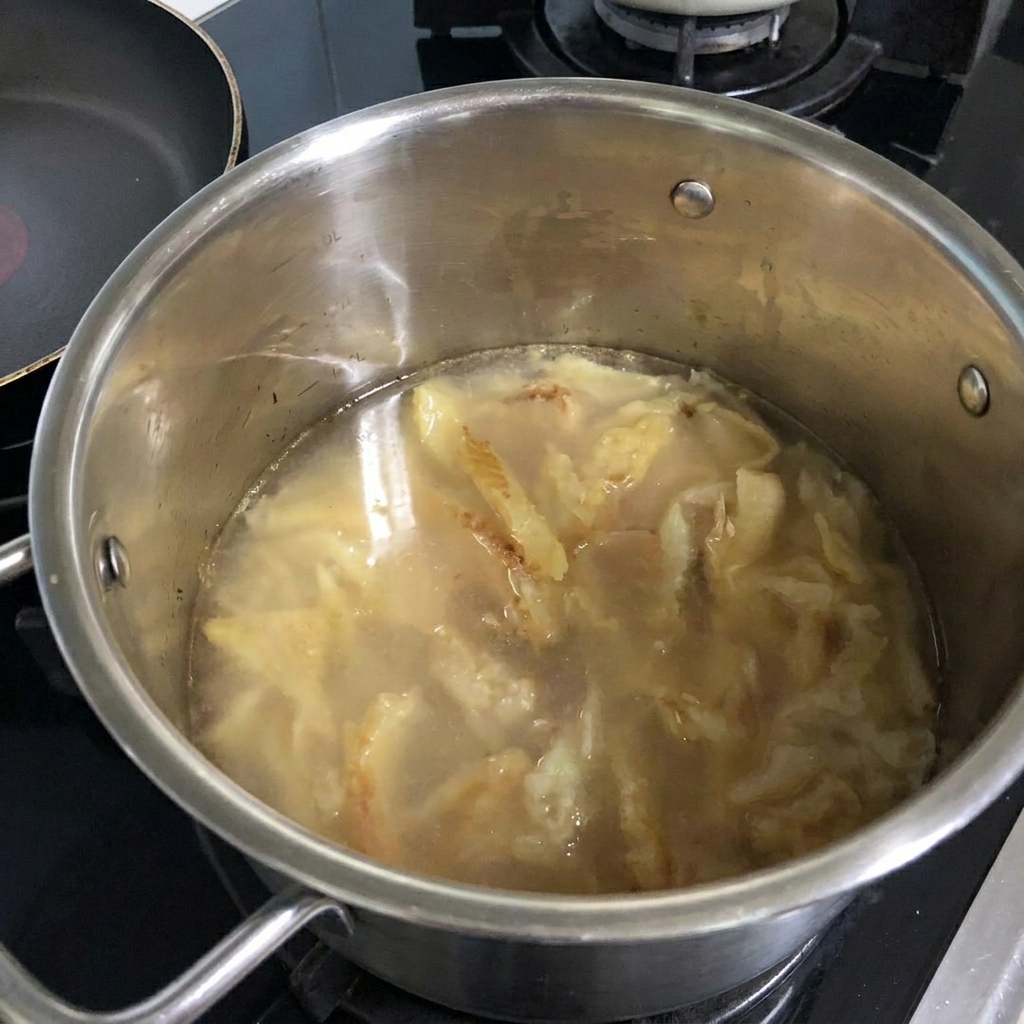 炒めたタラに水を注ぎ入れる様子。