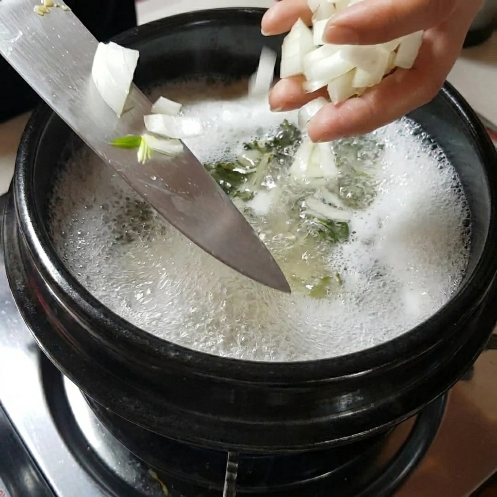 煮立っている鍋にスライスした玉ねぎとマッシュルームを加えている様子。