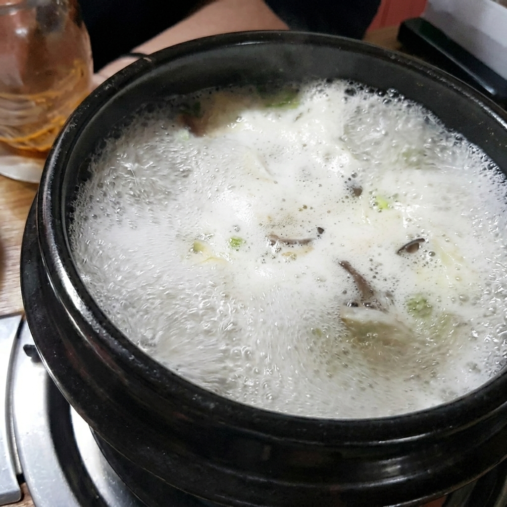 石鍋の中で茶色いテンジャンをスープに溶かし混ぜている様子。
