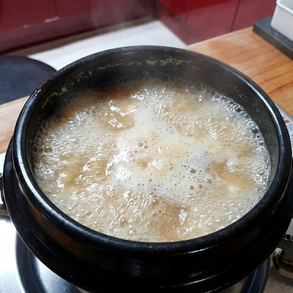 沸騰しているテンジャンチゲにおろしにんにくを加えている様子。