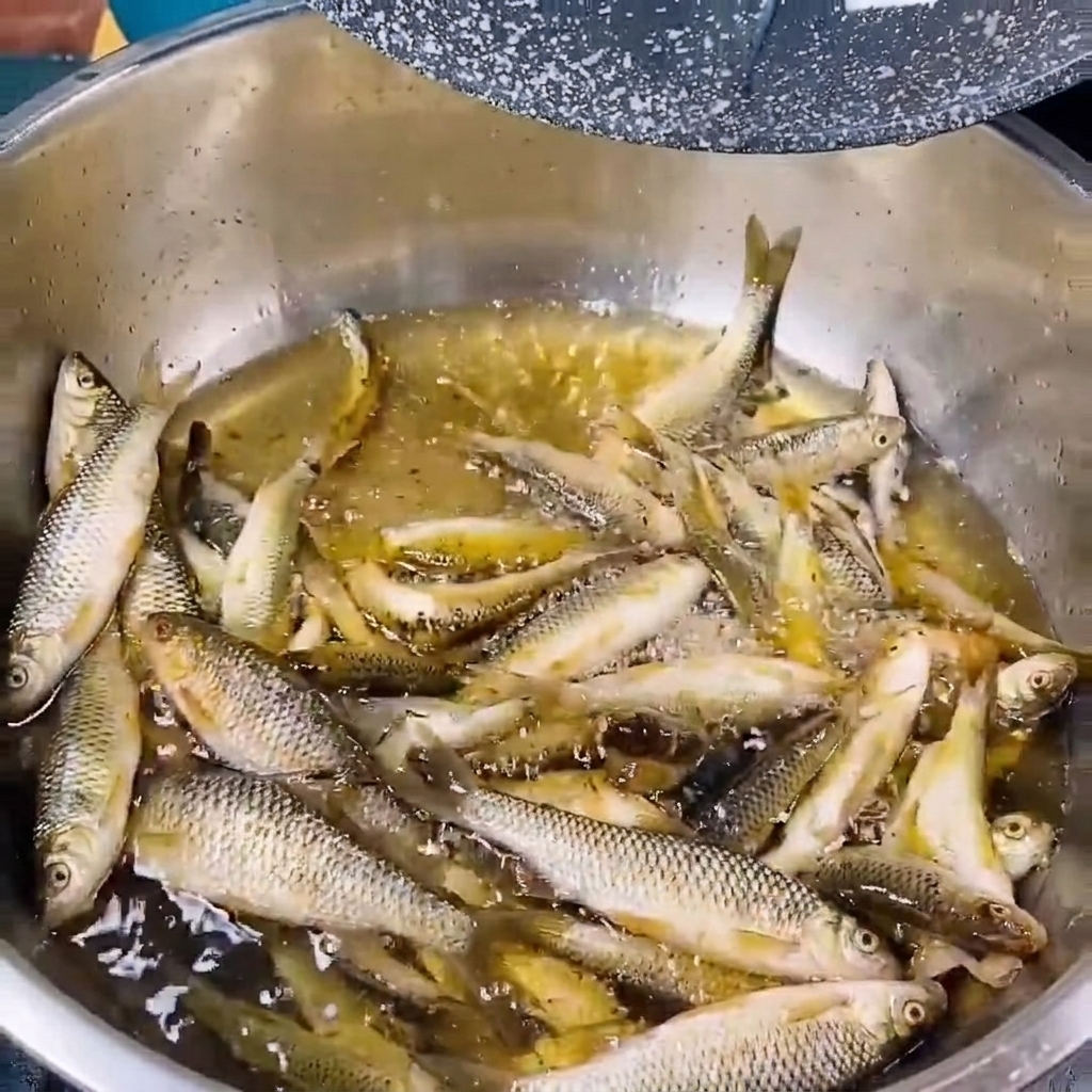 綺麗な水を入れた金属製のボウルで新鮮な小魚を洗う様子。