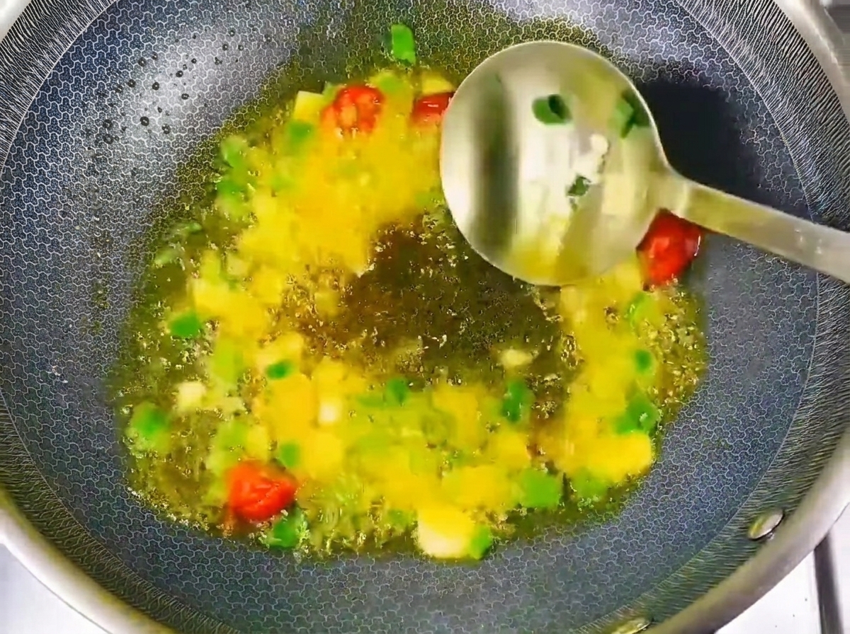中華鍋で炒めた香味野菜に豆醤と醤油を加えている様子。