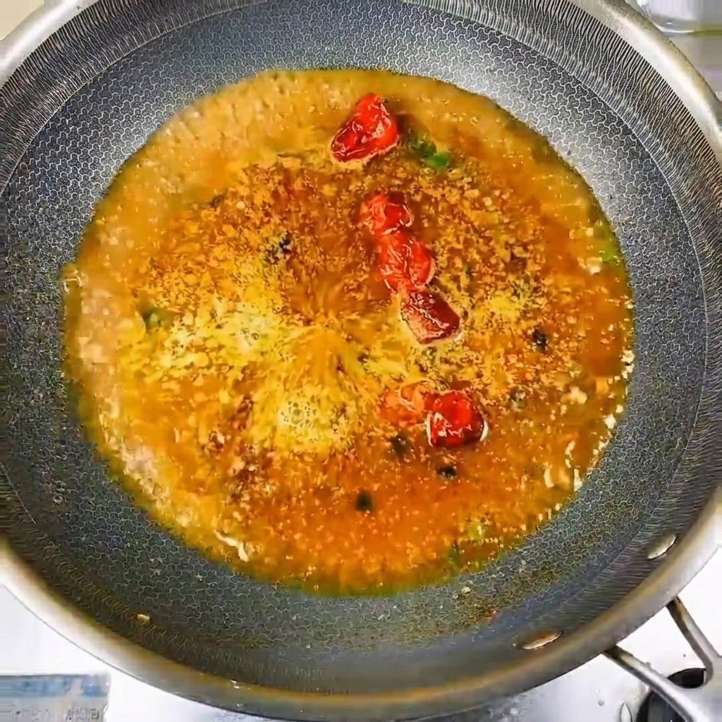 味付けされてグツグツと煮立つ煮汁の中に、新鮮な小魚を円状に綺麗に並べている様子。
