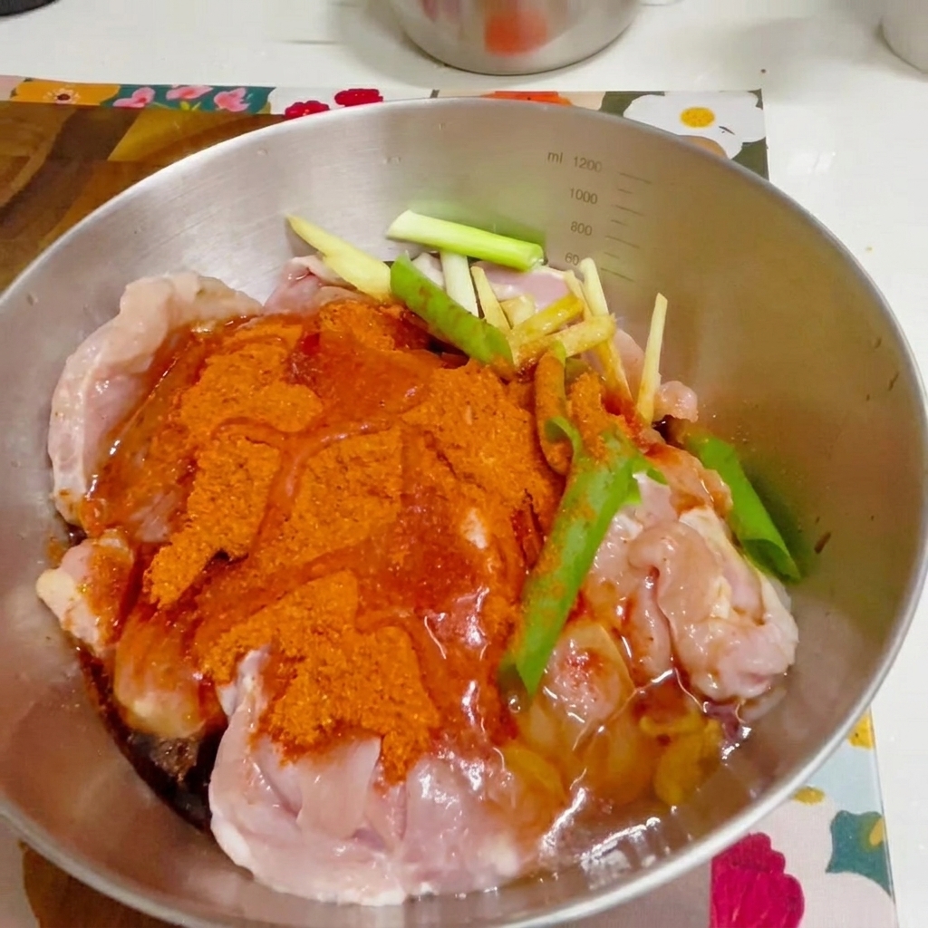手袋をした手で鶏肉と調味料を混ぜている様子