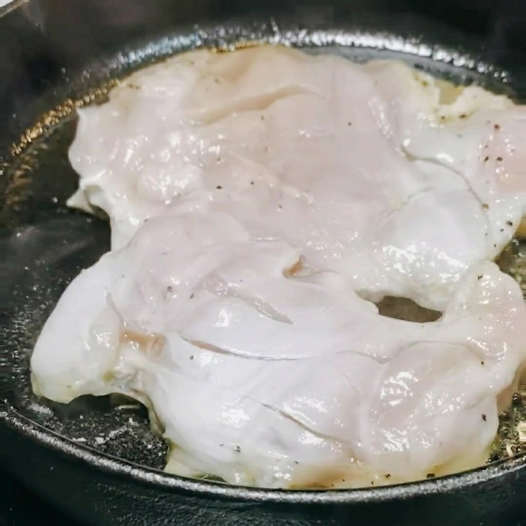 調理中の鶏肉に照り焼きソースと白ワインをかけて煮込んでいる様子。
