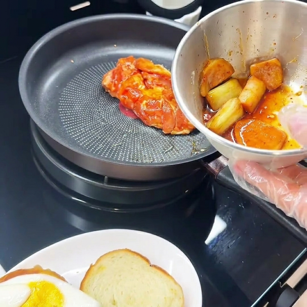 マリネした鶏肉を皮目からフライパンで焼いている様子。