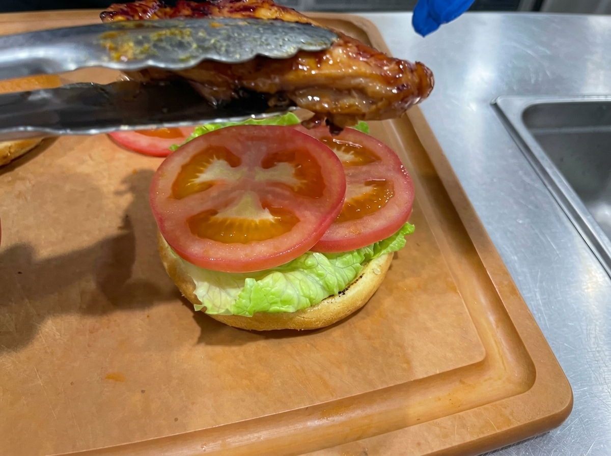 トマトの上に照り焼きチキンをのせている様子。