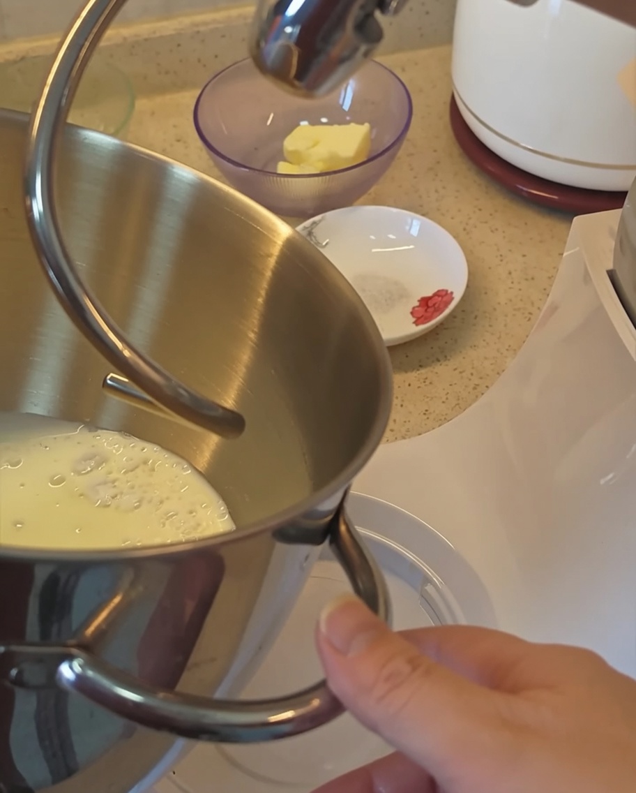 バンズ生地用の粉類と牛乳が入ったスタンドミキサーのボウルのクローズアップ。