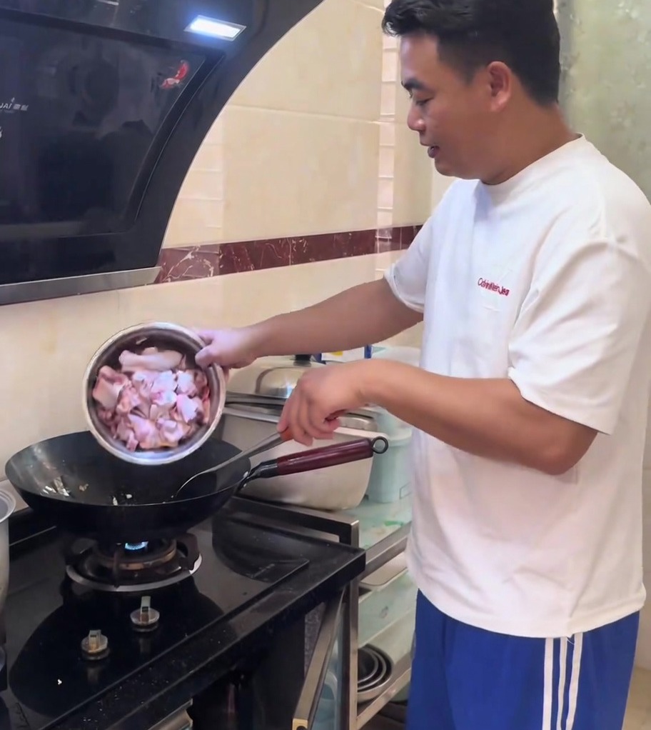 熱した中華鍋の中で、鶏肉とみじん切りにした生姜を炒めている様子。