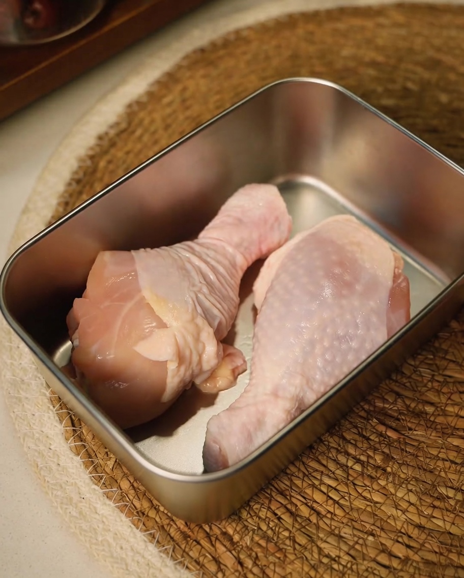 キッチンバサミで鶏もも肉をトリミングしている様子。