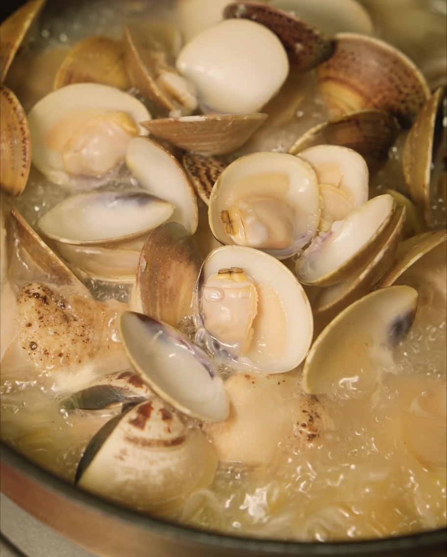 鶏スープにあさりを加えて蓋をしている様子。