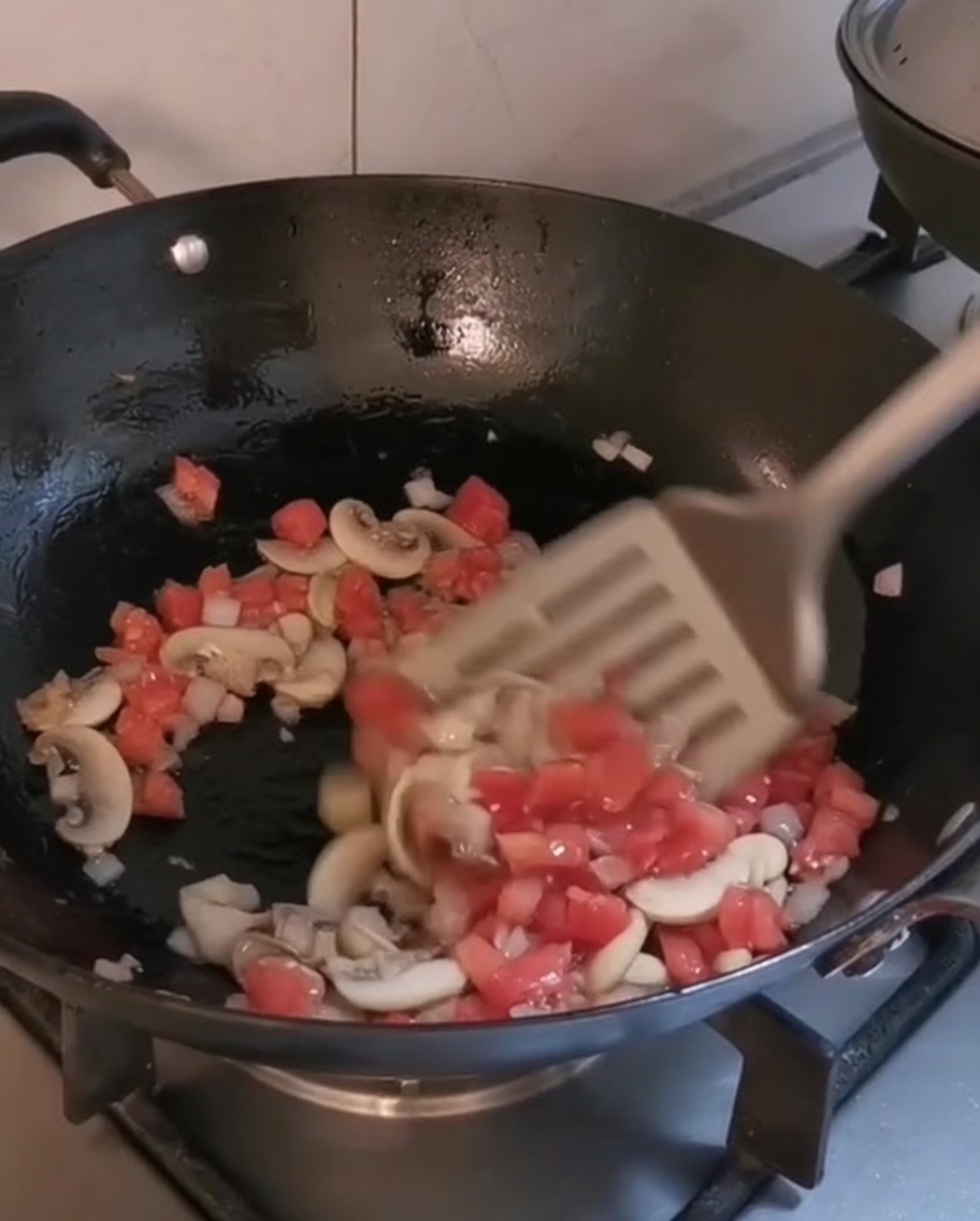 オリーブオイルを引いた熱いフライパンで炒められている野菜とマッシュルーム。