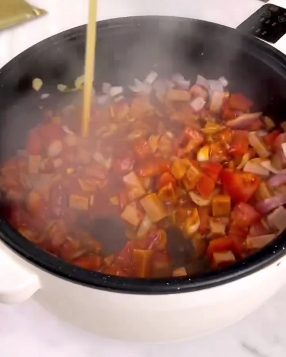炒めた具材の中にパスタソースを投入している様子。
