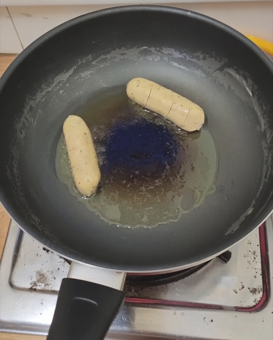 フライパンで焼かれている目玉焼きとソーセージ。