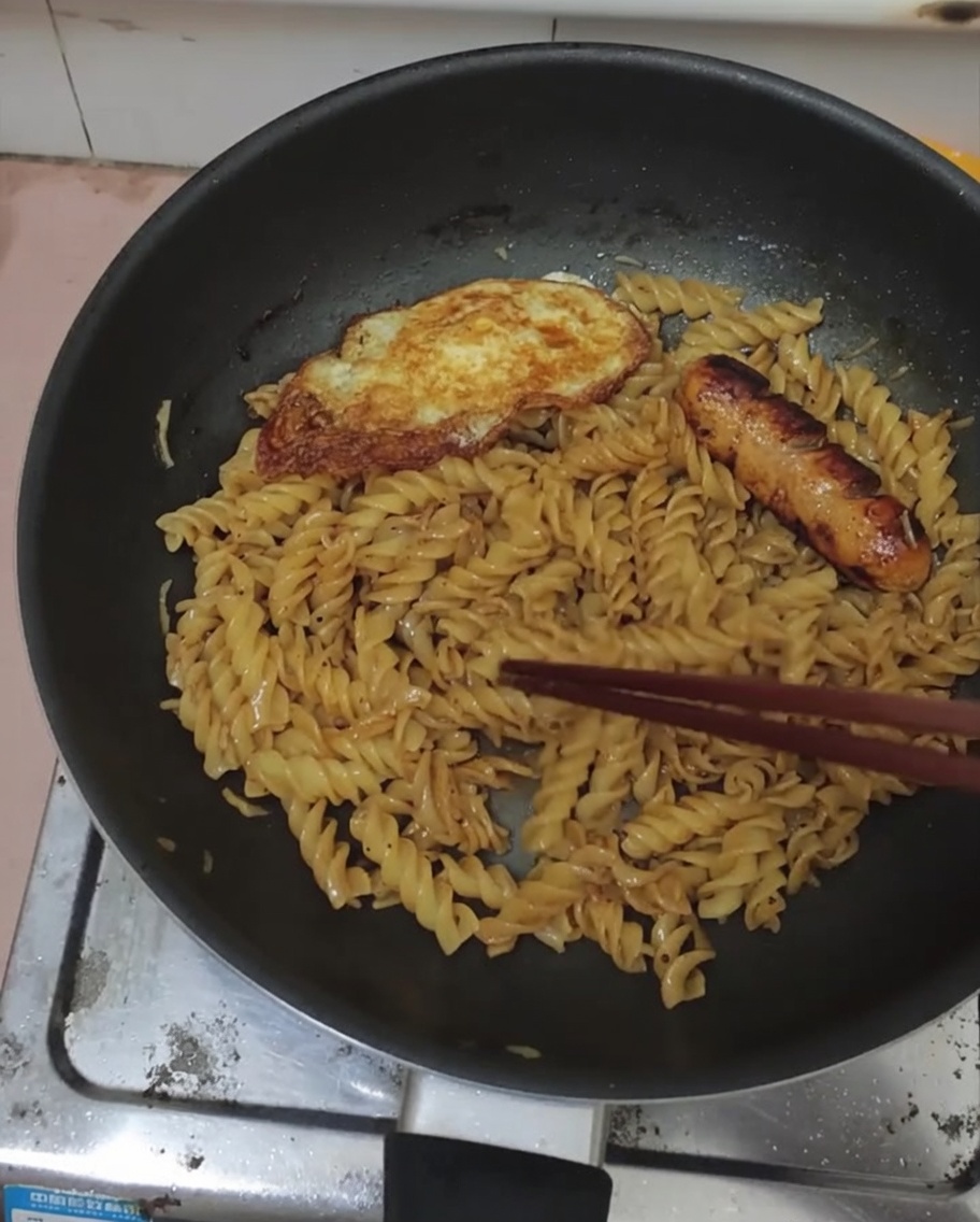 黒胡椒フジッリの上に目玉焼きとソーセージが盛り付けられた完成品。