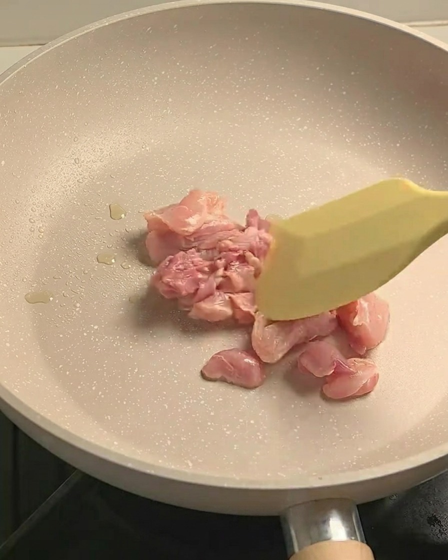 フライパンで鶏肉を炒め、焼き色をつけている様子。