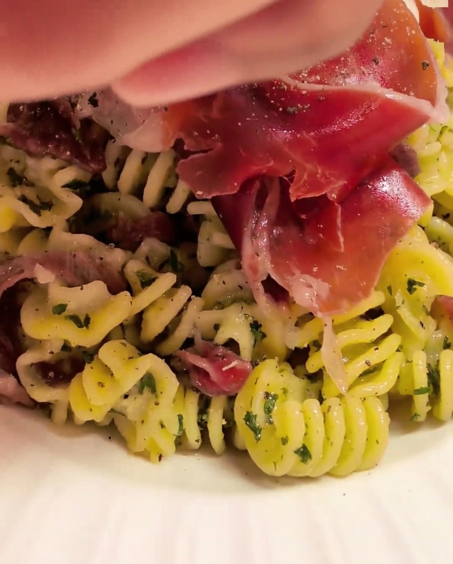トングを使ってパスタにソースをしっかり絡めている様子。